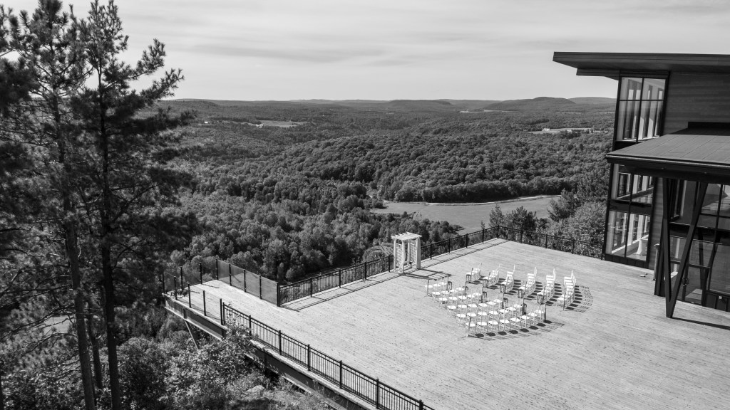 Vue panoramique d'une terrasse avec des chaises disposées en cercle, entourée de forêts verdoyantes à l'auberge de la Montagne Coupée.
