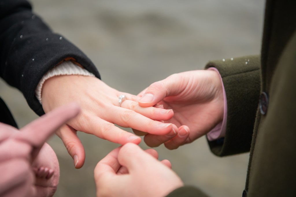 Deux personnes échangent une bague de fiançailles, montrant une main avec une bague brillante sur l'annulaire.