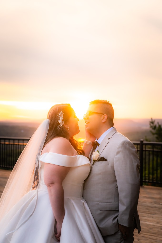 Un couple en train de s'embrasser au coucher du soleil, avec un paysage romantique en arrière-plan.
