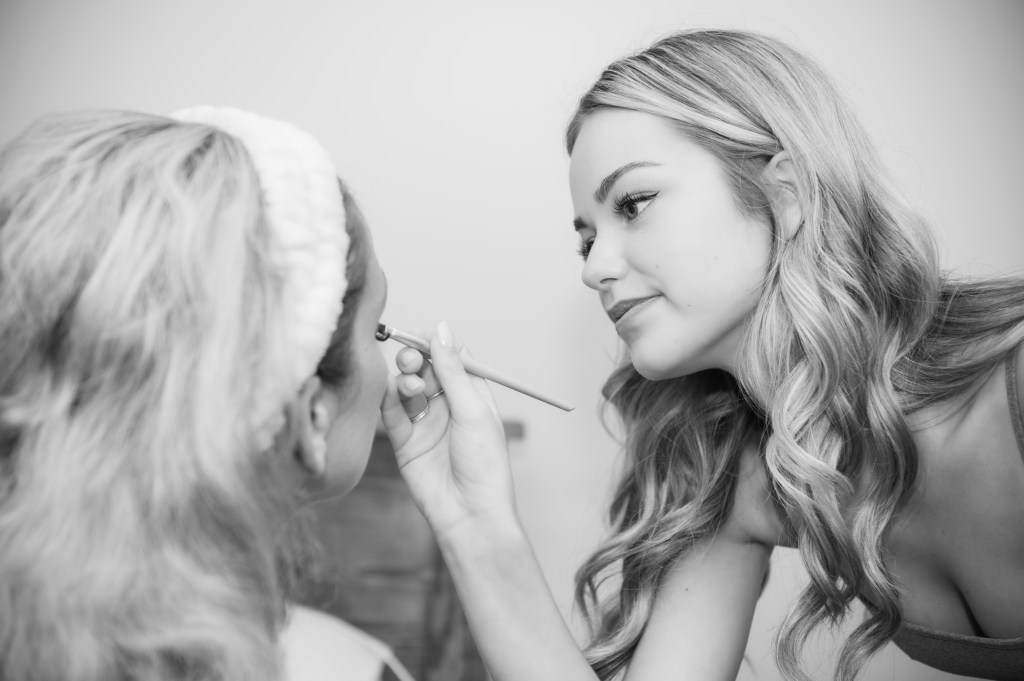 Une maquilleuse appliquant du maquillage sur le visage d'une cliente dans un environnement lumineux.