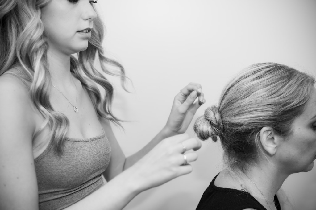 Une jeune femme coiffe une autre femme avec un chignon, en mettant l'accent sur les détails de la coiffure.